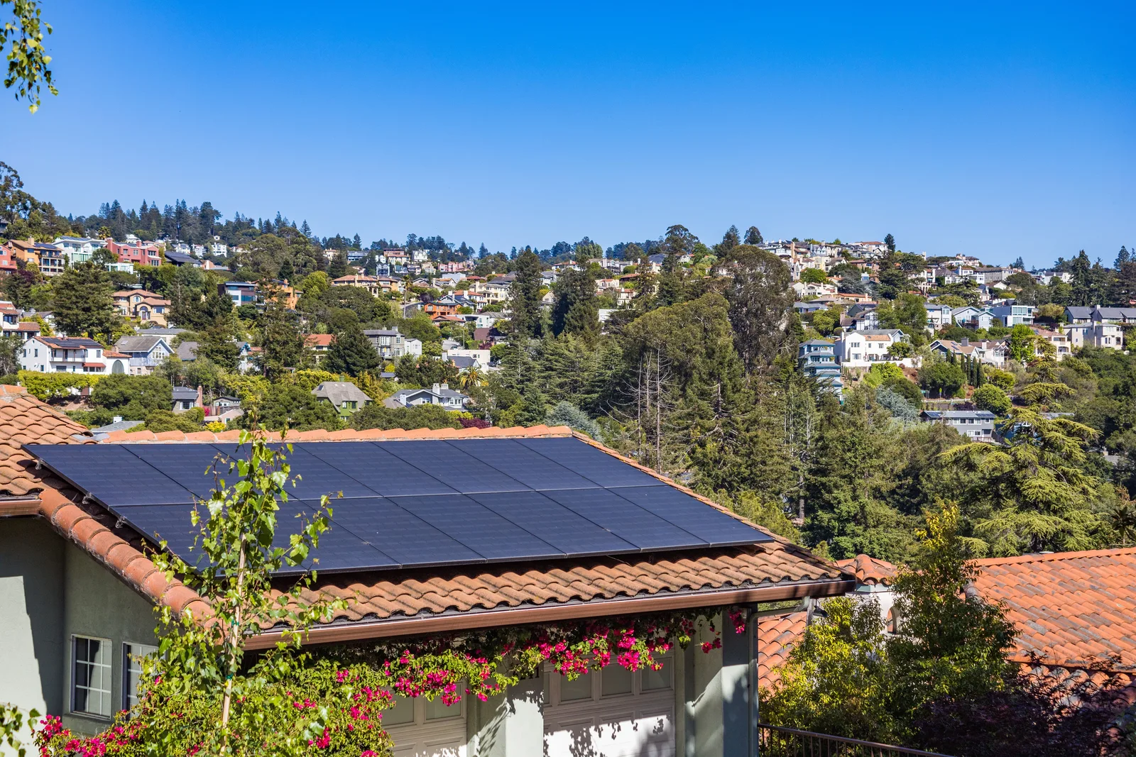 Rooftop solar panels on a hillside home above the neighborhood