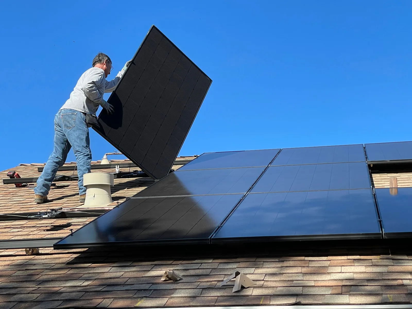 Installer lifting a solar panel into place on a residential roof