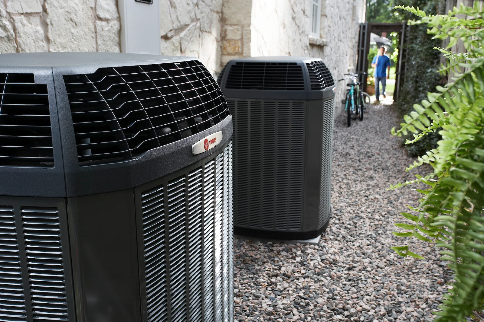 Two Trane outdoor units installed beside a home