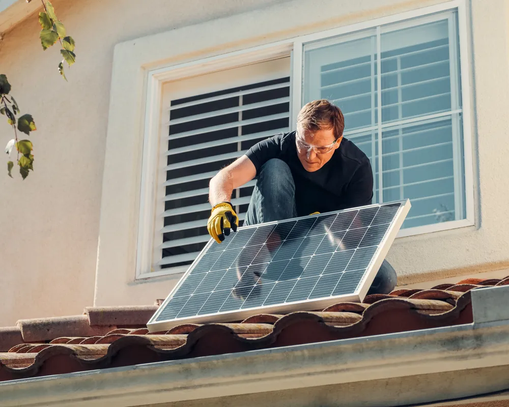 Installer fitting a solar panel onto the edge of a tile roof