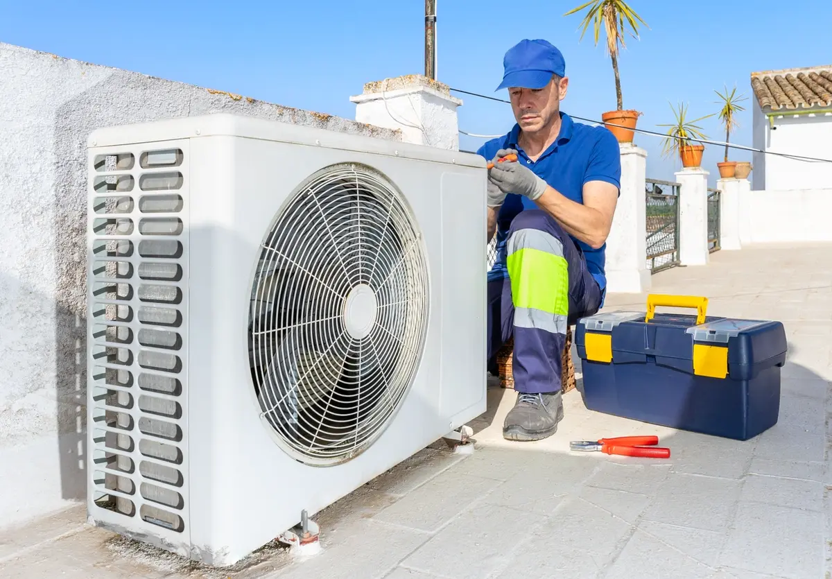 Technician standing beside an outdoor heat pump unit